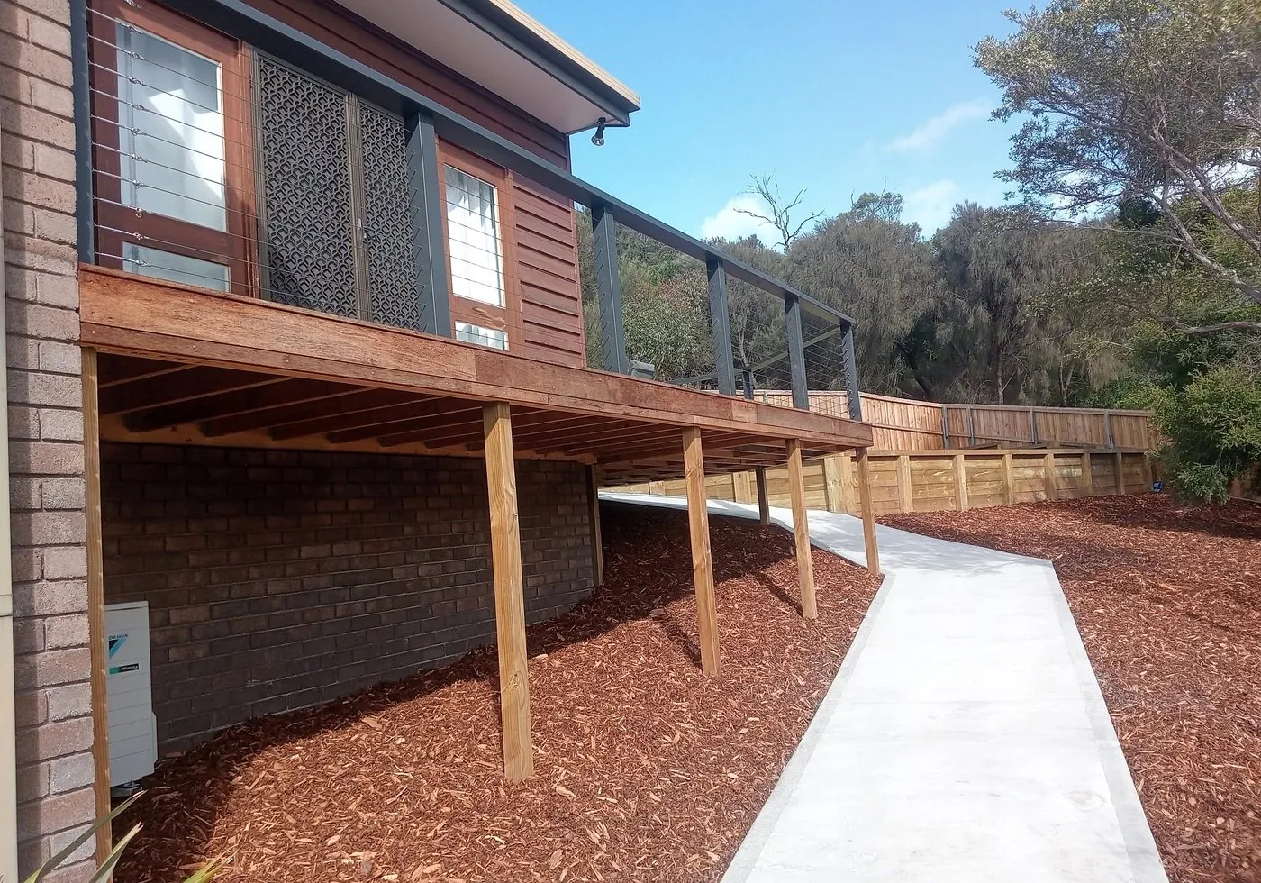 Elevated timber deck with a new concrete path and mulched yard