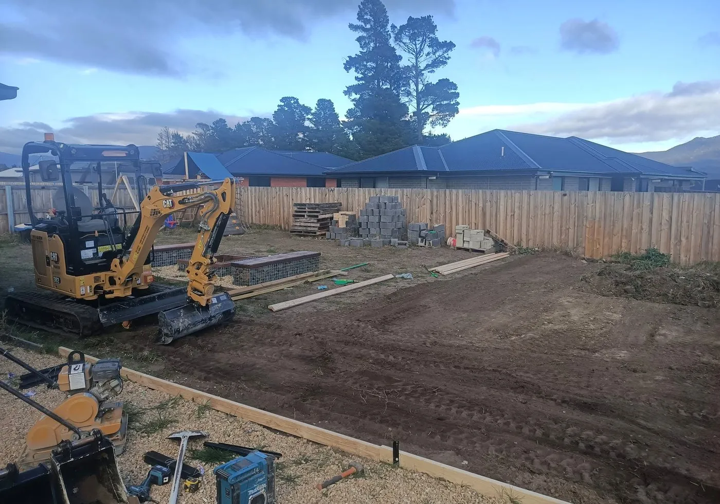 Compact excavator shaping a residential yard during earthworks