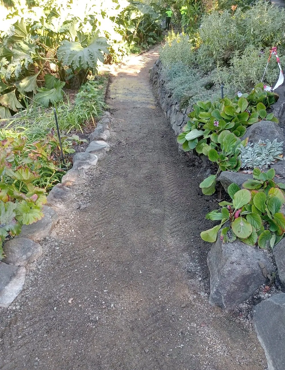 Compacted garden path base edged with natural stone